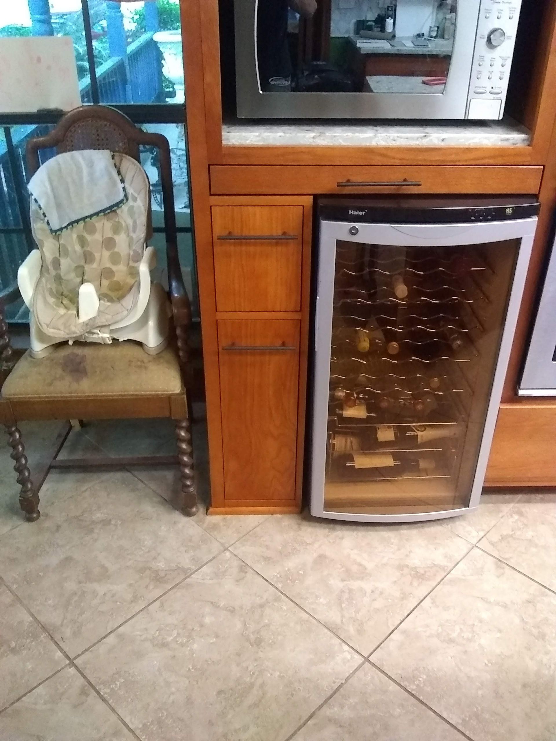 A chair is sitting next to a wine cooler in a kitchen.
