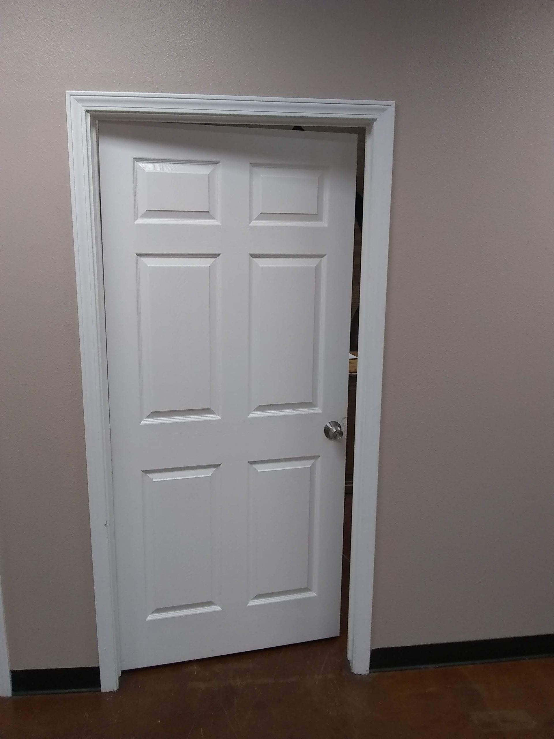 A white door is open in a room with a wooden floor.