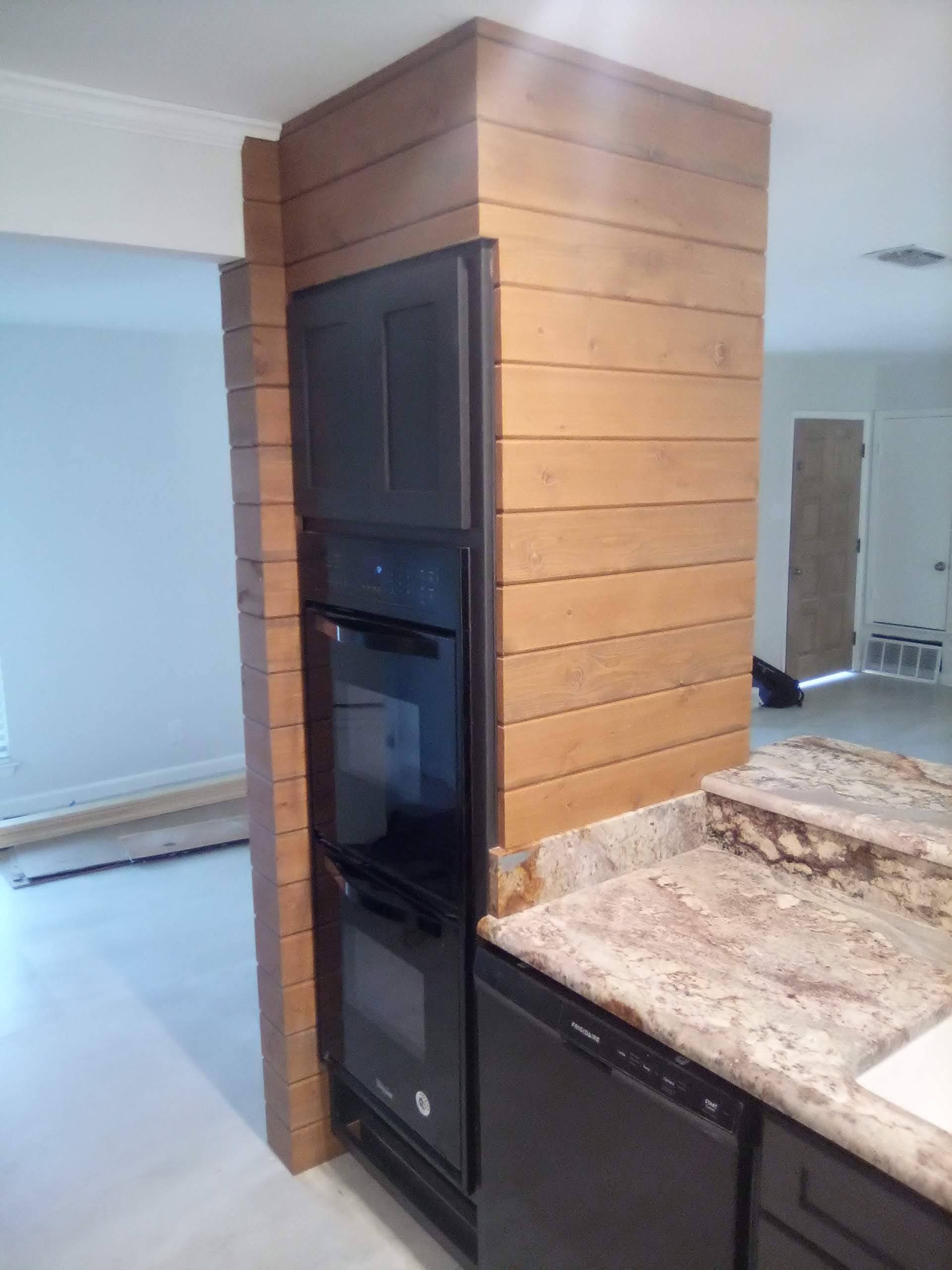 A kitchen with a wooden wall and a black oven