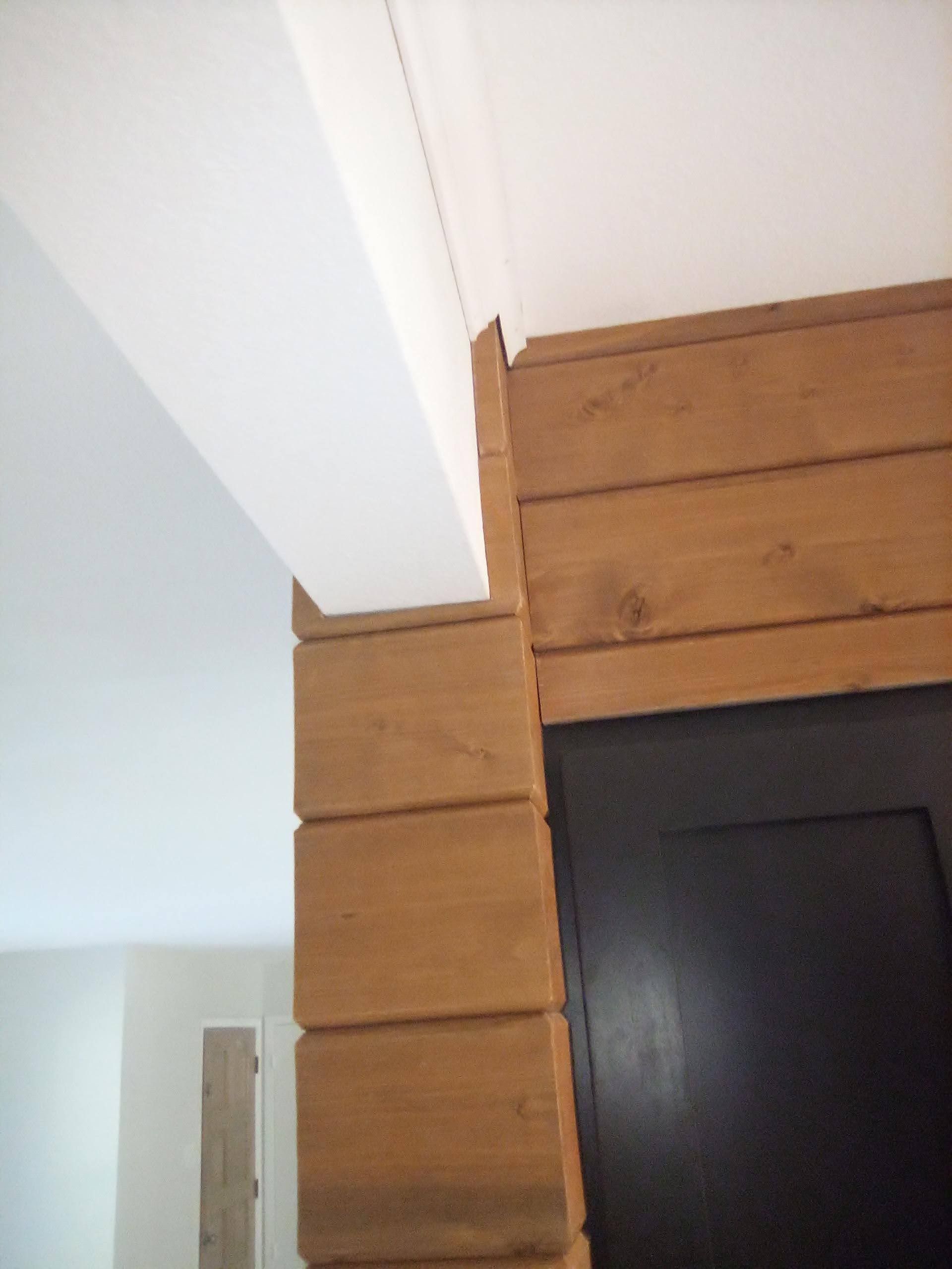 A wooden wall with a white ceiling and a black door