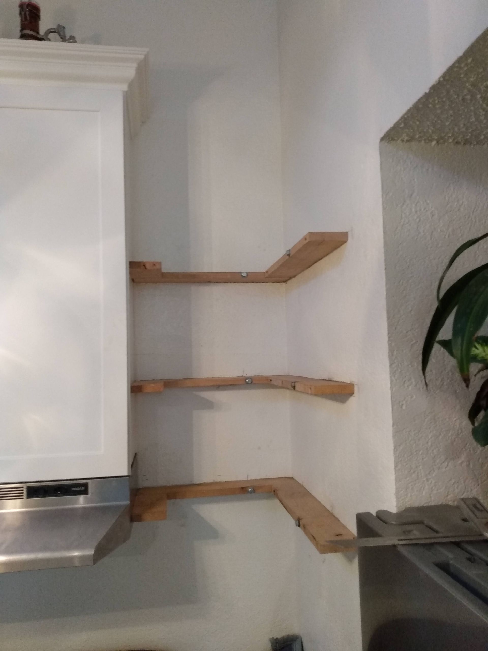 A kitchen with white cabinets and wooden shelves