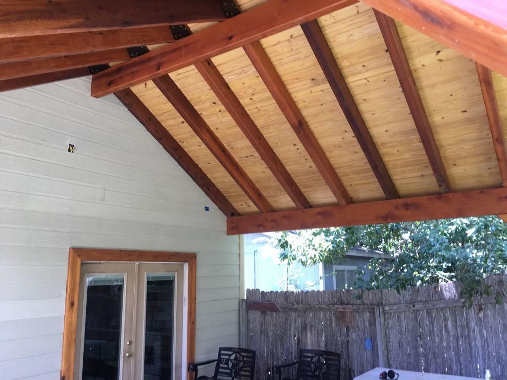 A patio with a wooden roof and a table and chairs