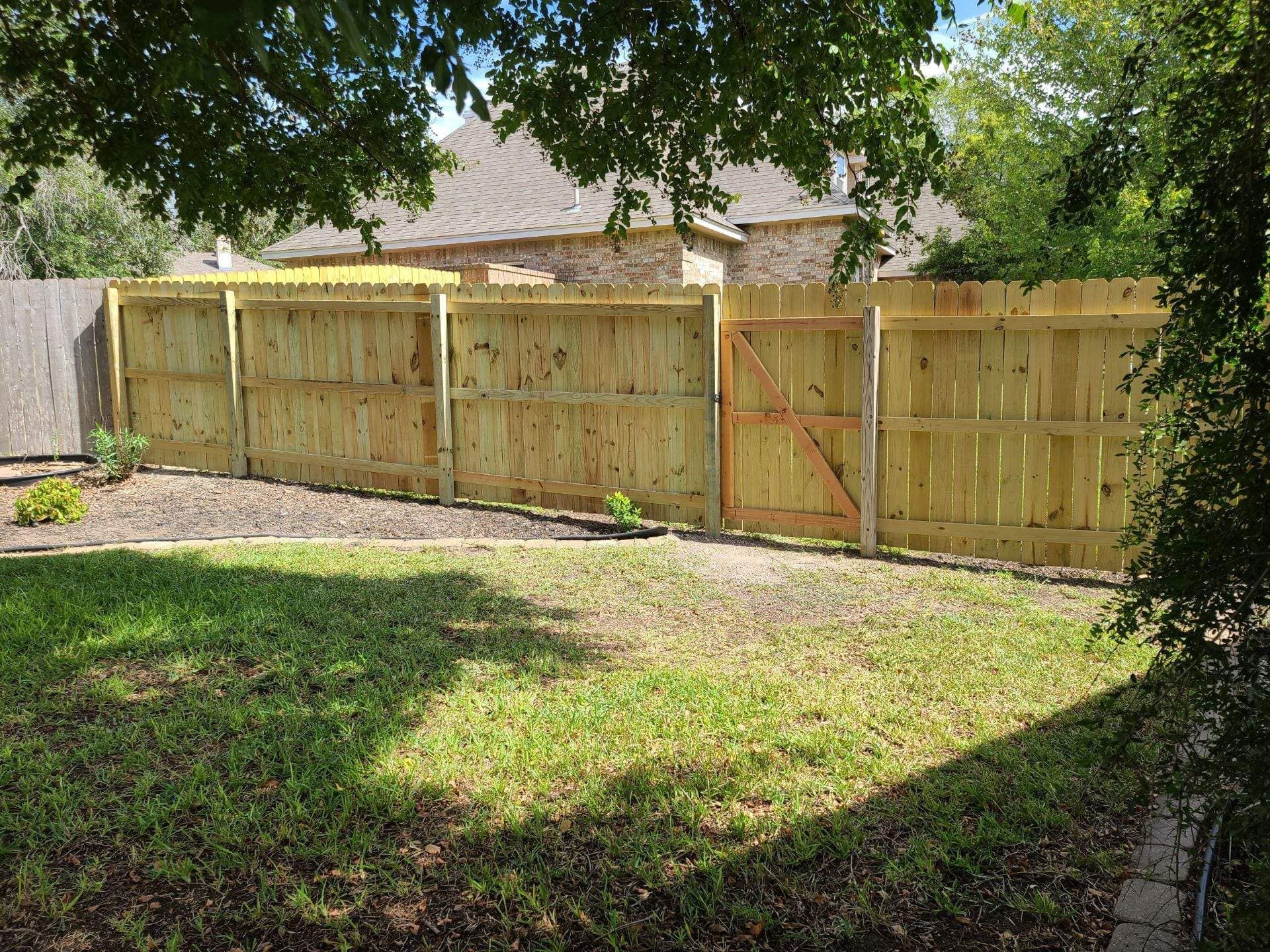 A wooden fence is in the backyard of a house.