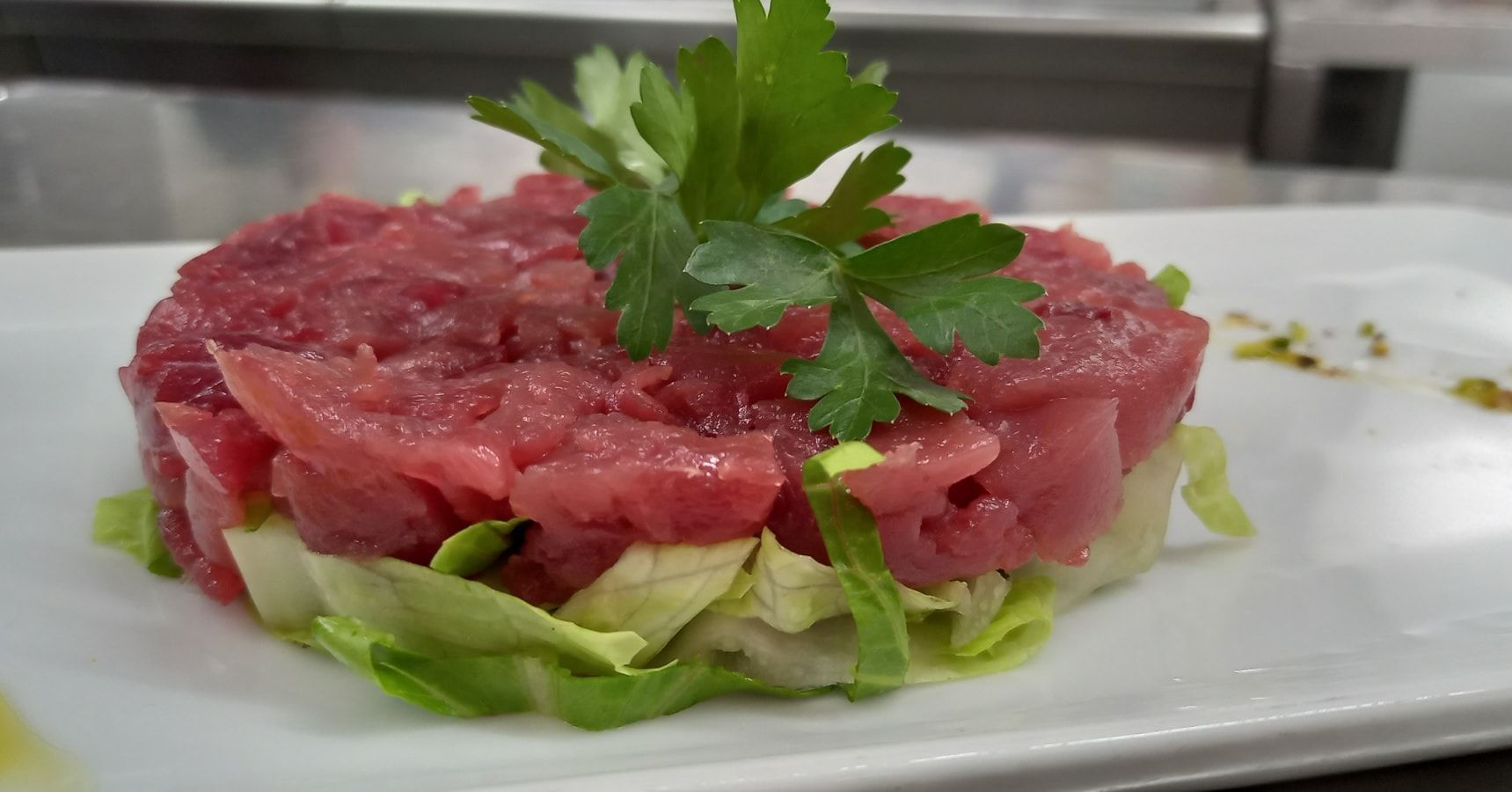 Un piatto bianco sormontato da un pezzo di carne e lattuga.