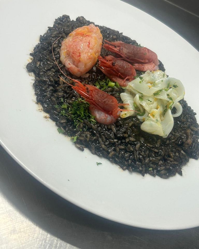 Un piatto bianco con riso nero e gamberi