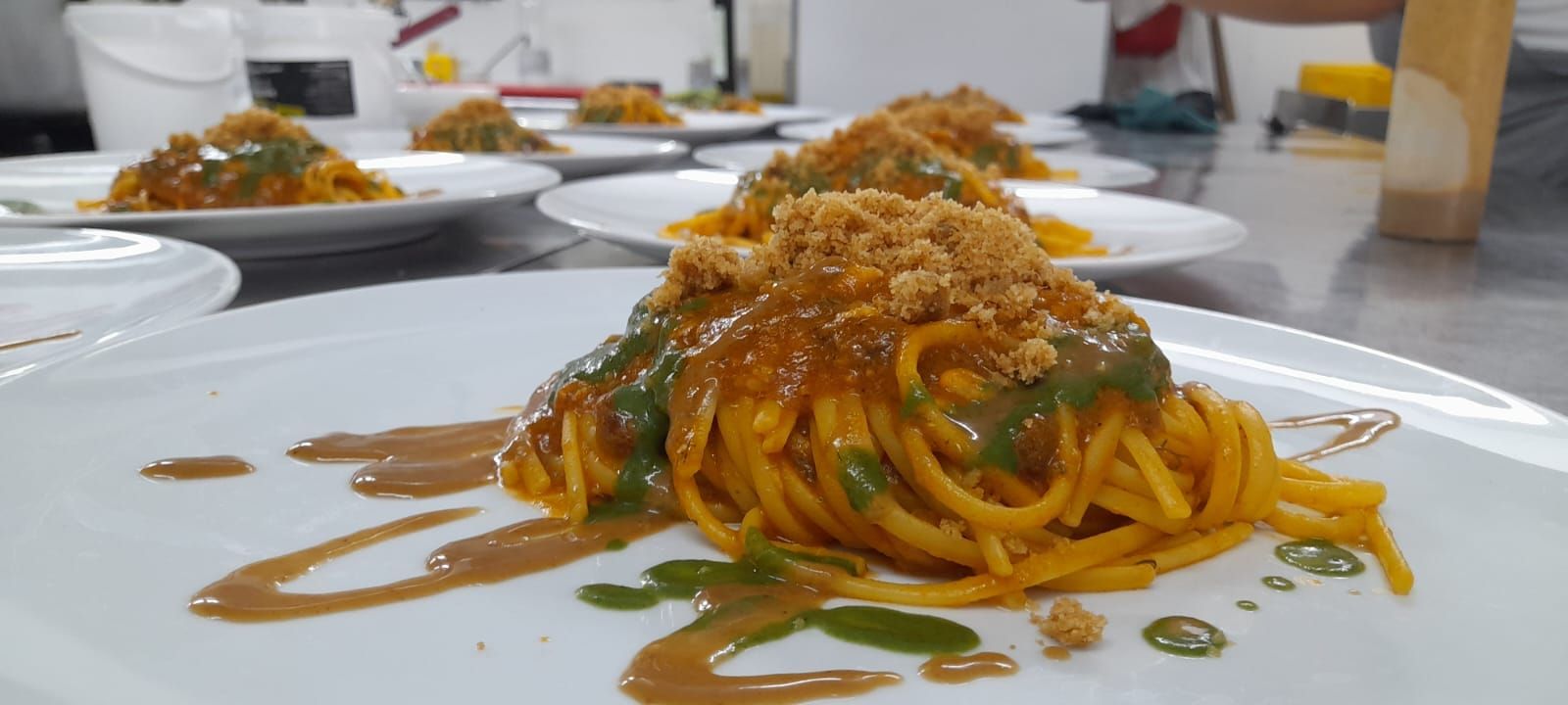 Un piatto bianco con sopra tagliatelle e salsa su un tavolo.