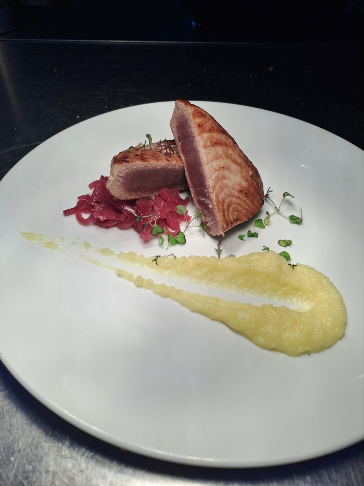 Un piatto bianco con un pezzo di carne sopra