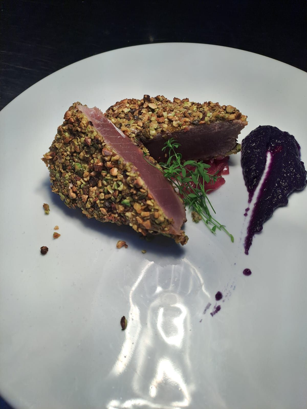 Un piatto bianco sormontato da un pezzo di carne e salsa