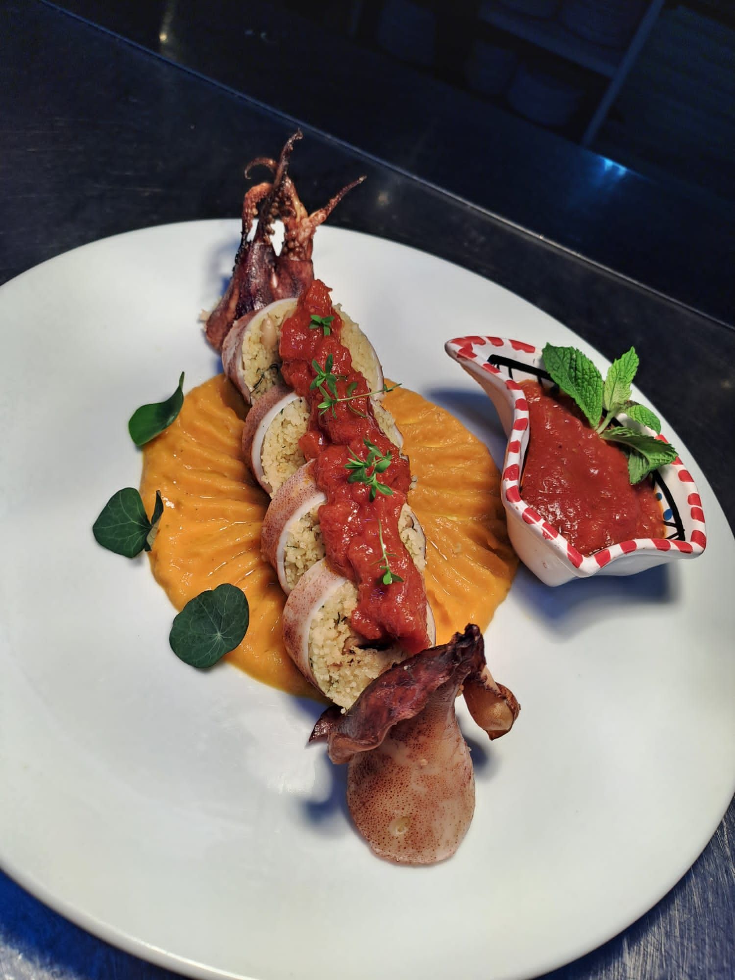 Un piatto bianco con carne e salsa accanto a una piccola ciotola di salsa