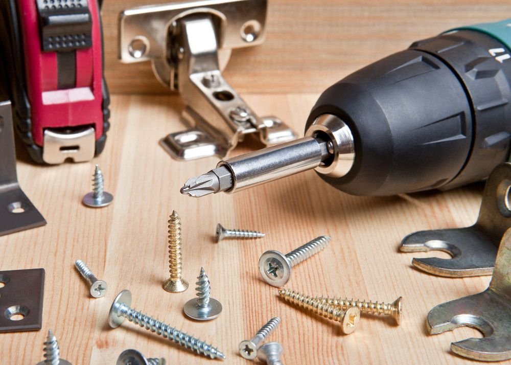 A Drill Is Sitting On A Wooden Table Surrounded By Screws And Other Tools — Wallers Precision Tooling In Paget, QLD