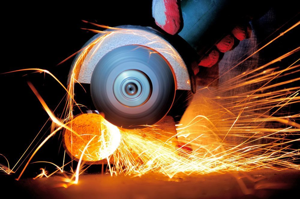 A Person Is Grinding A Piece Of Metal With Sparks Coming Out Of It — Wallers Precision Tooling In Mackay, QLD