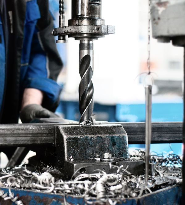 A Person Is Using A Machine To Drill A Hole In A Piece Of Metal — Wallers Precision Tooling In Mackay, QLD