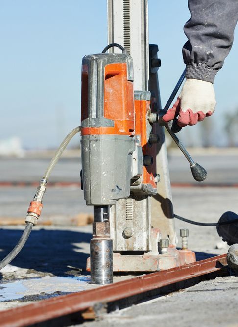 A Person Is Using A Drill On A Construction Site — Wallers Precision Tooling In Mackay, QLD