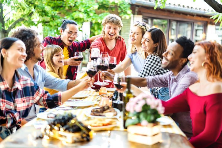 Friend group laughing and enjoying food/drinks.