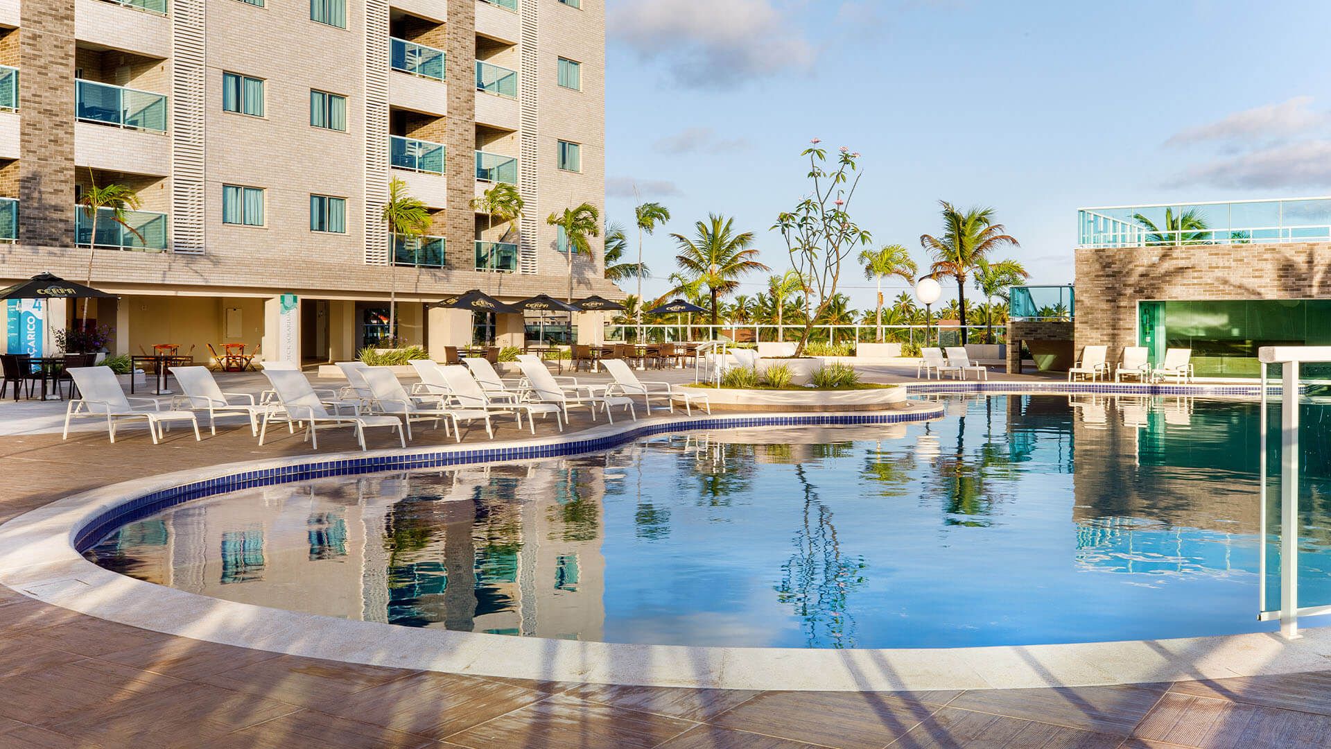 Há uma grande piscina em frente a um hotel.