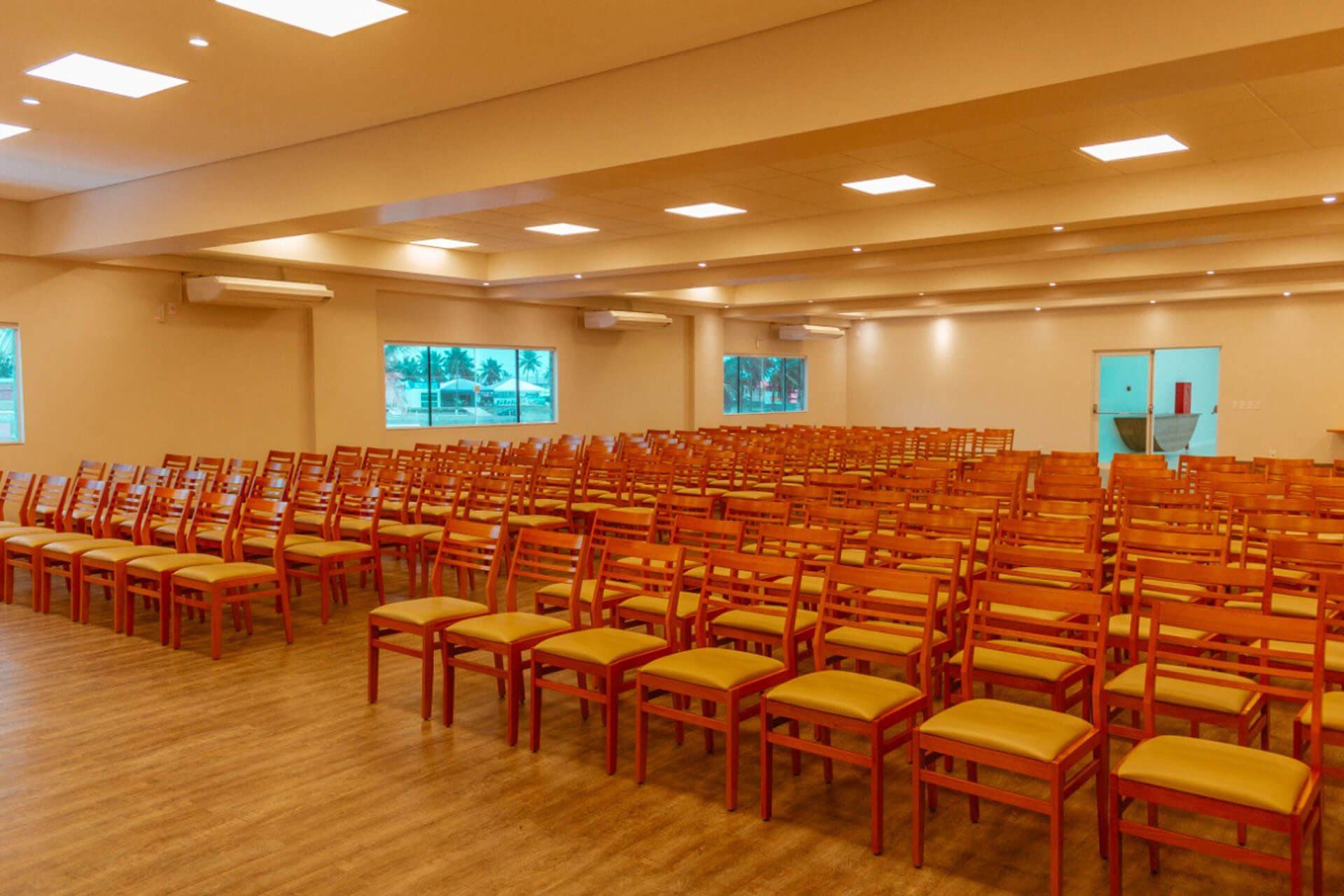 Uma grande sala cheia de fileiras de cadeiras de madeira.