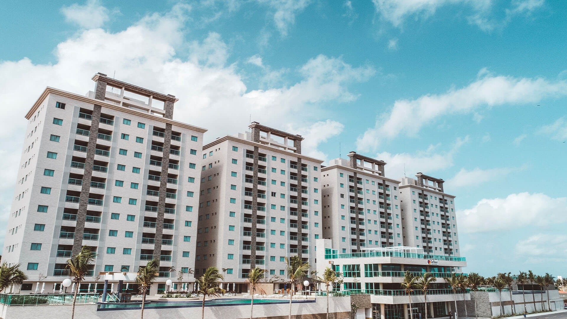 Uma fileira de edifícios altos contra um céu azul com nuvens.