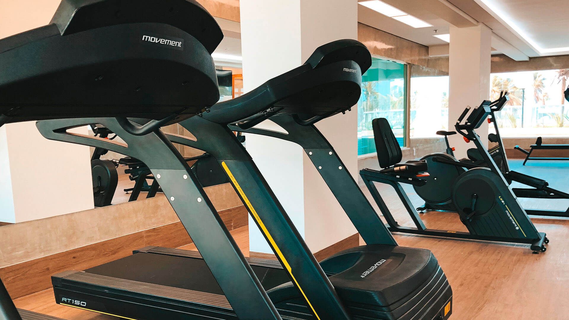 Uma fileira de esteiras estão alinhadas em uma academia.