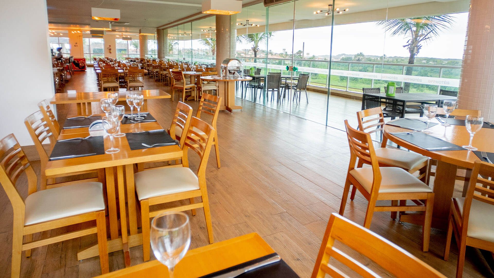 Um restaurante com mesas e cadeiras e uma taça de vinho na mesa