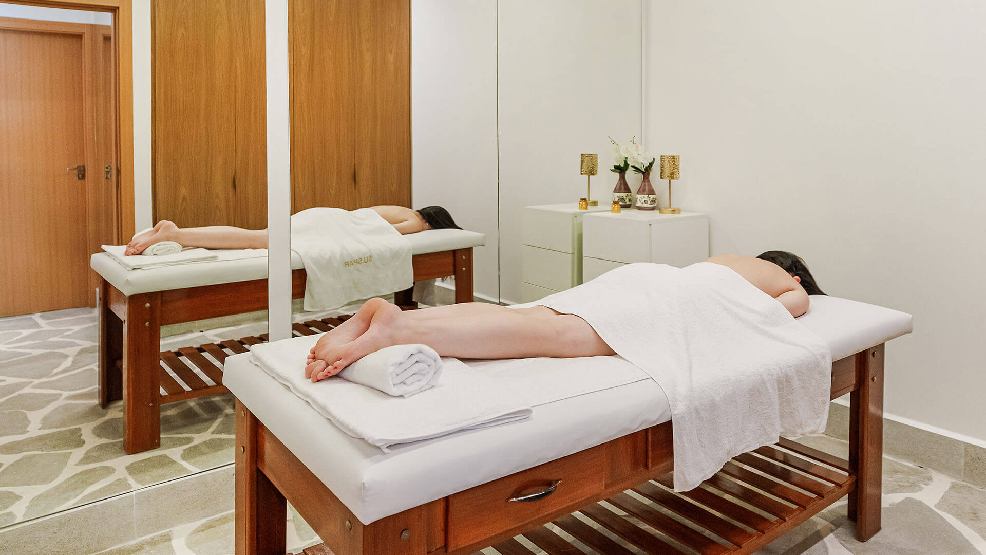 Uma mulher está deitada em uma mesa de massagem em frente a um espelho.