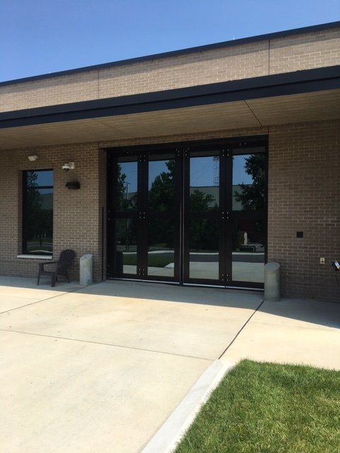 Exterior view of a building with large glass doors and brick walls; sunny day.