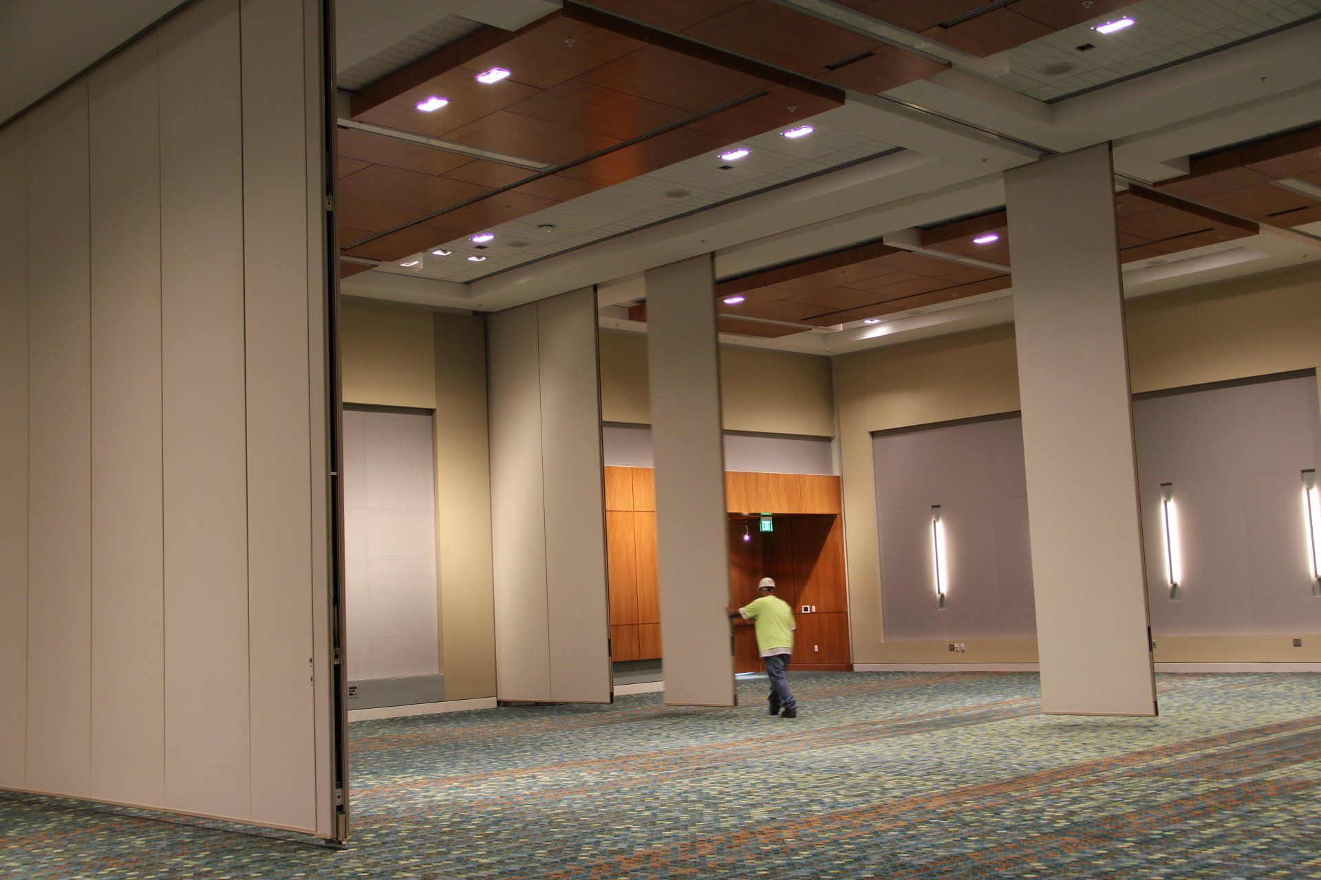 Large room with partially extended, movable wall panels; a person stands near a door.