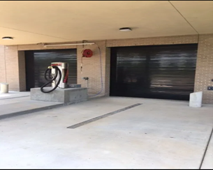 Twin black garage doors behind charging pedestal. Twin black garage doors behind charging pedestal.