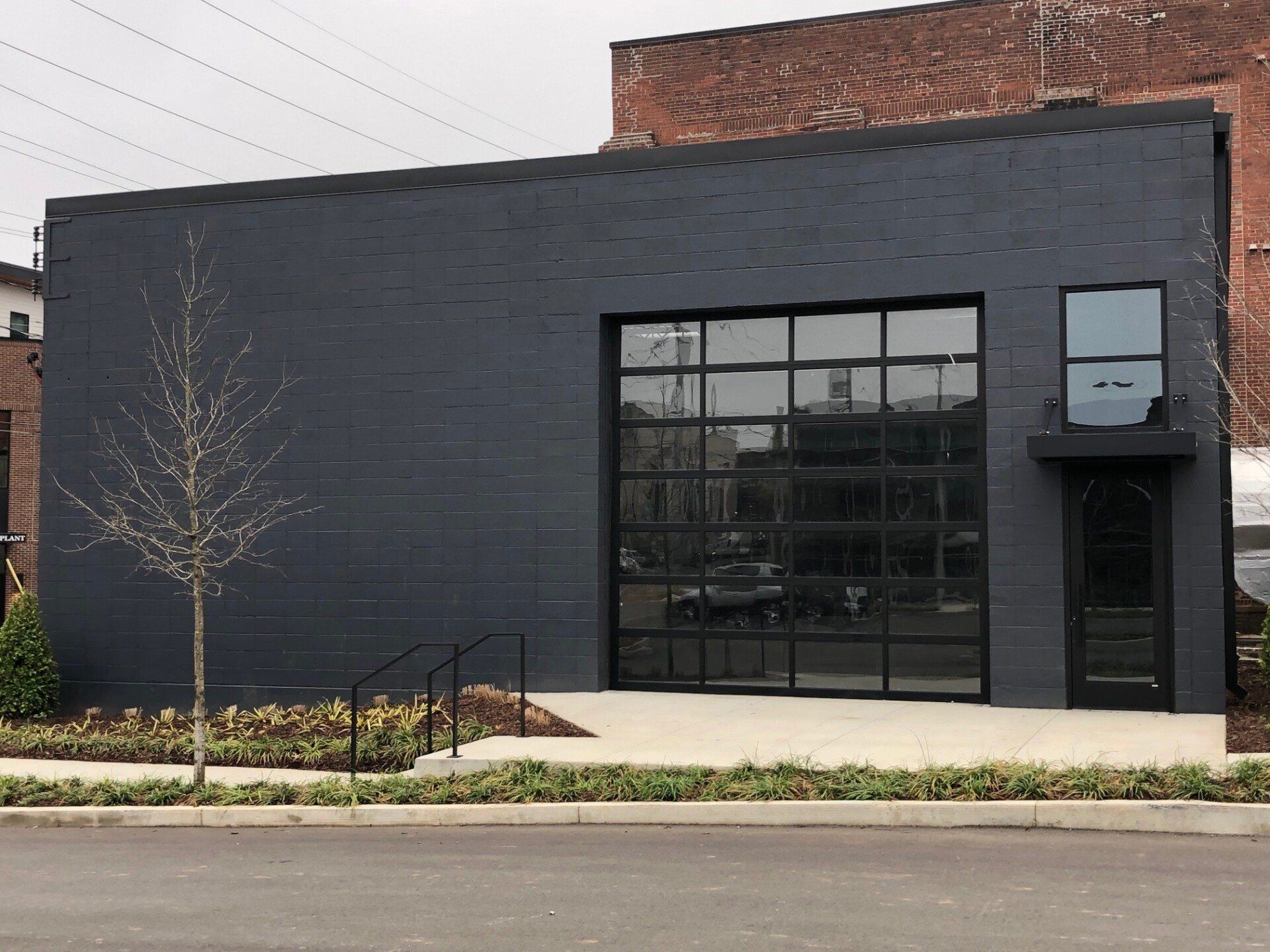 Black brick building with large glass door, small window, and entrance.