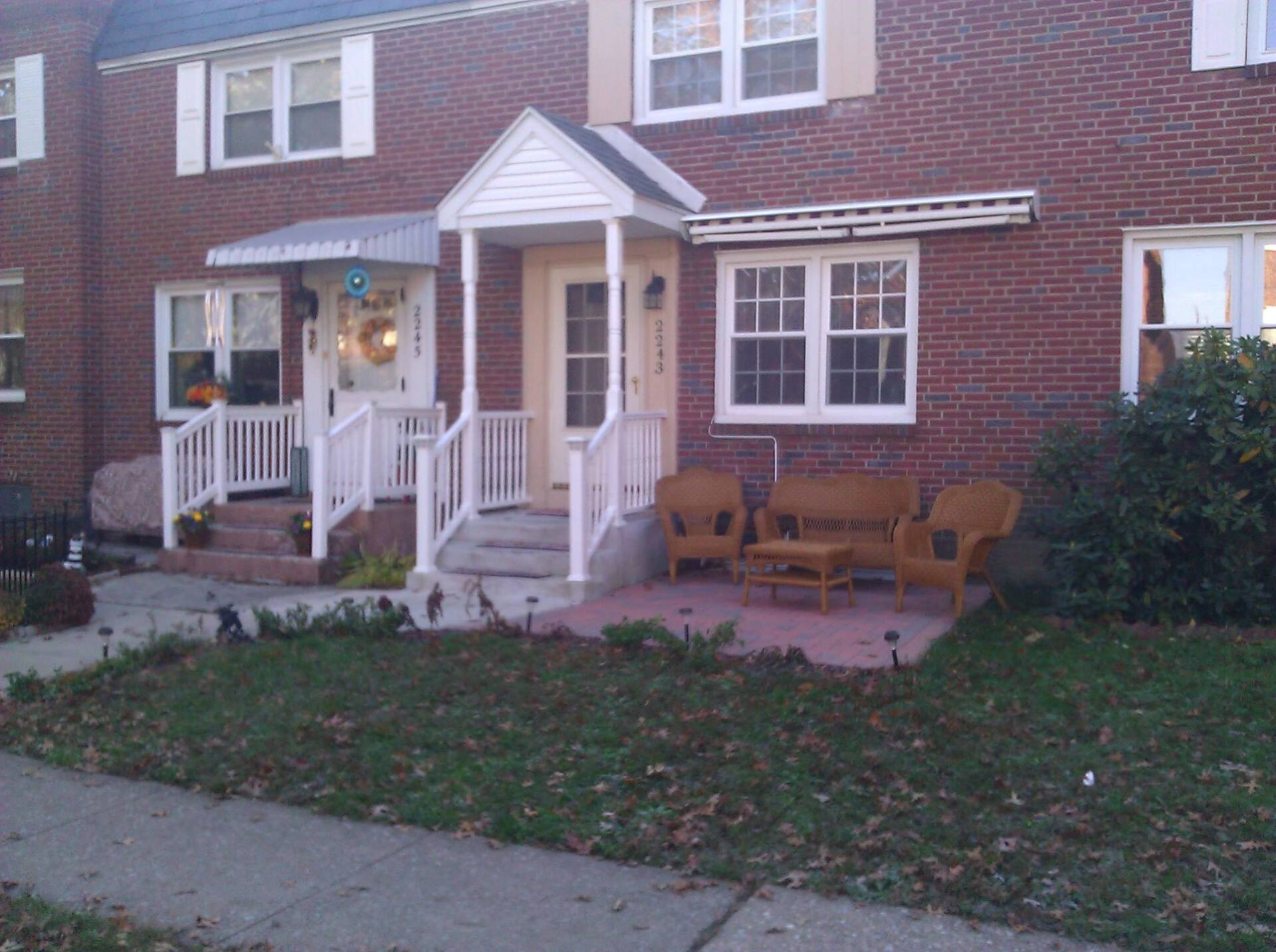 A brick house with a porch and chairs in front of it