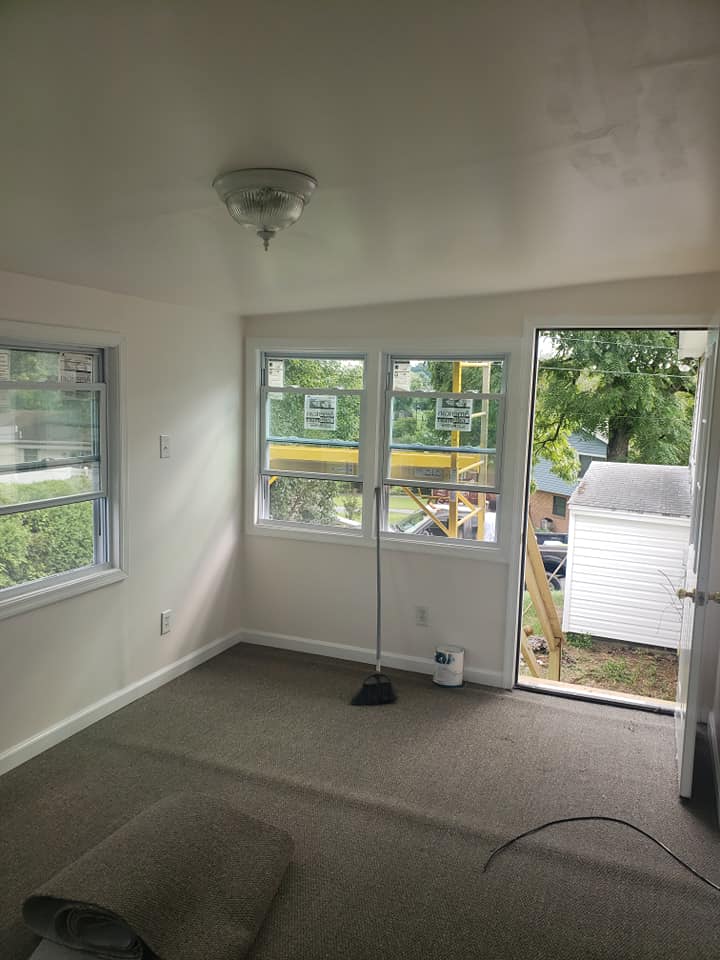 A room with a lot of windows and a broom in it.