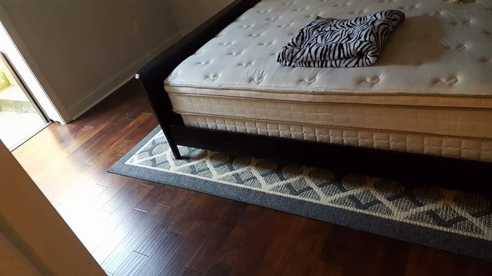 A bed with a mattress and a rug on the floor.
