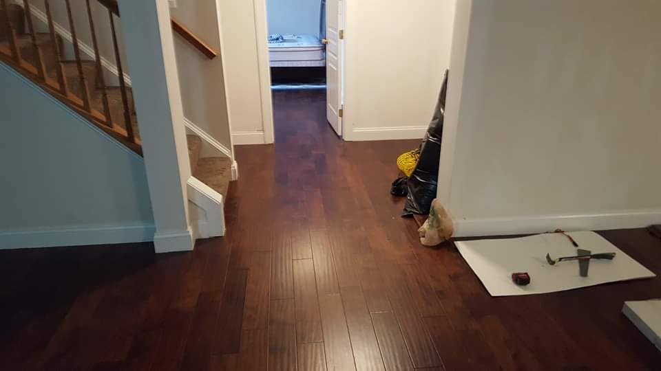 A hallway with hardwood floors and stairs in a house.