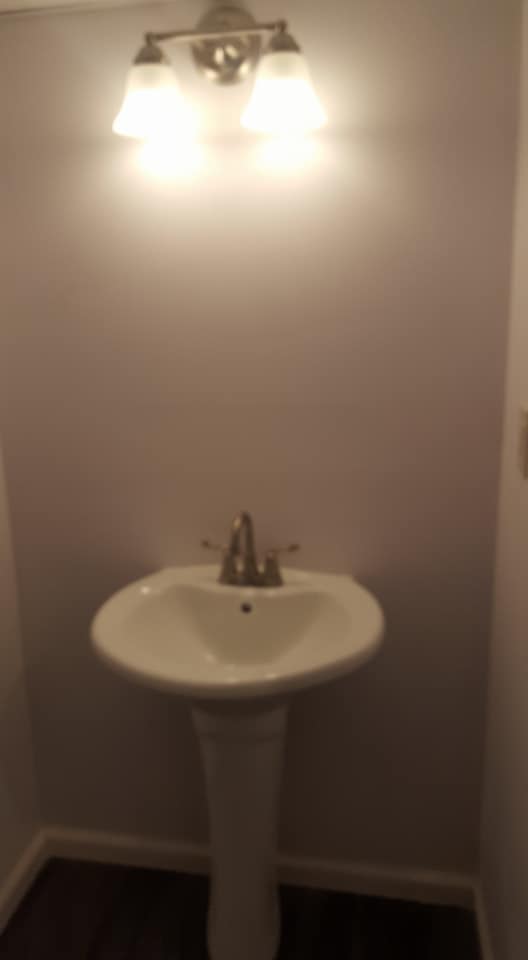 A bathroom with a pedestal sink and a light above it.
