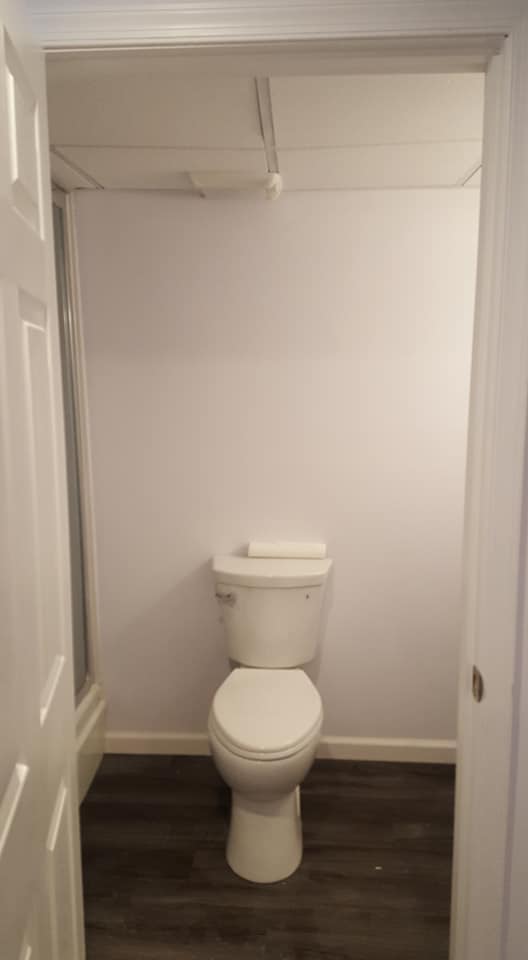 A toilet is sitting in a bathroom next to a door.