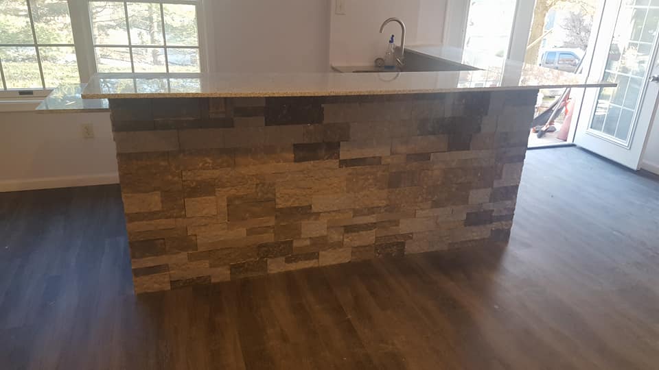 A kitchen with a stone counter top and a sink.