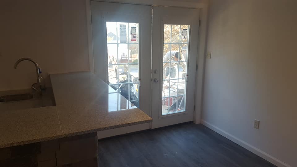 A kitchen with a sink , sliding glass doors and a window.