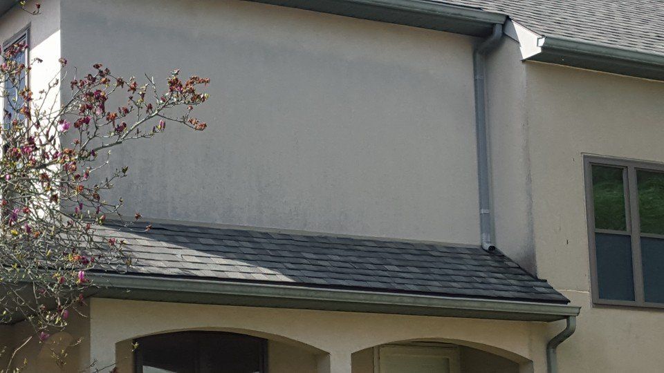 A house with a gutter on the side of it and a roof.