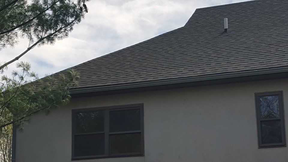 The back of a house with a roof and two windows.