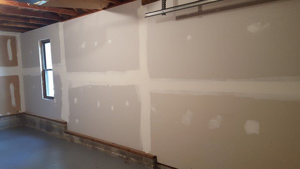 A garage with drywall walls and a window.