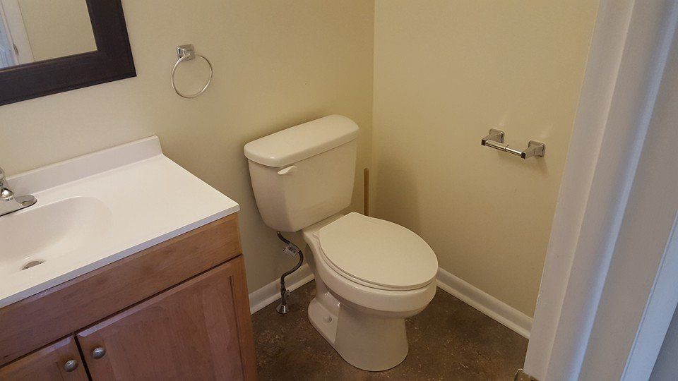 A bathroom with a toilet , sink and mirror.