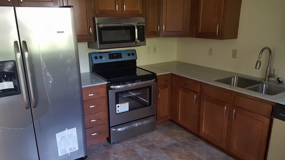 A kitchen with a stove , refrigerator , microwave and sink.