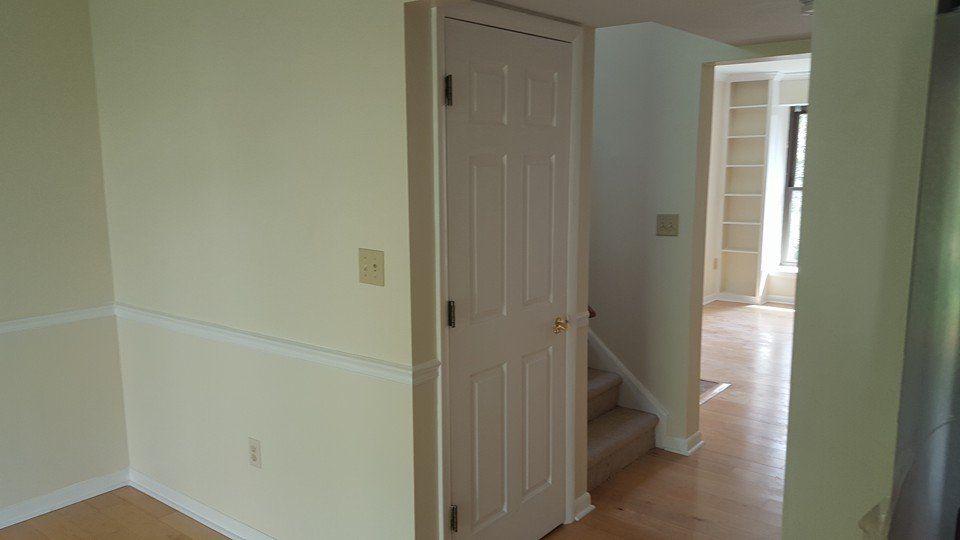 A hallway with a door and stairs in a house
