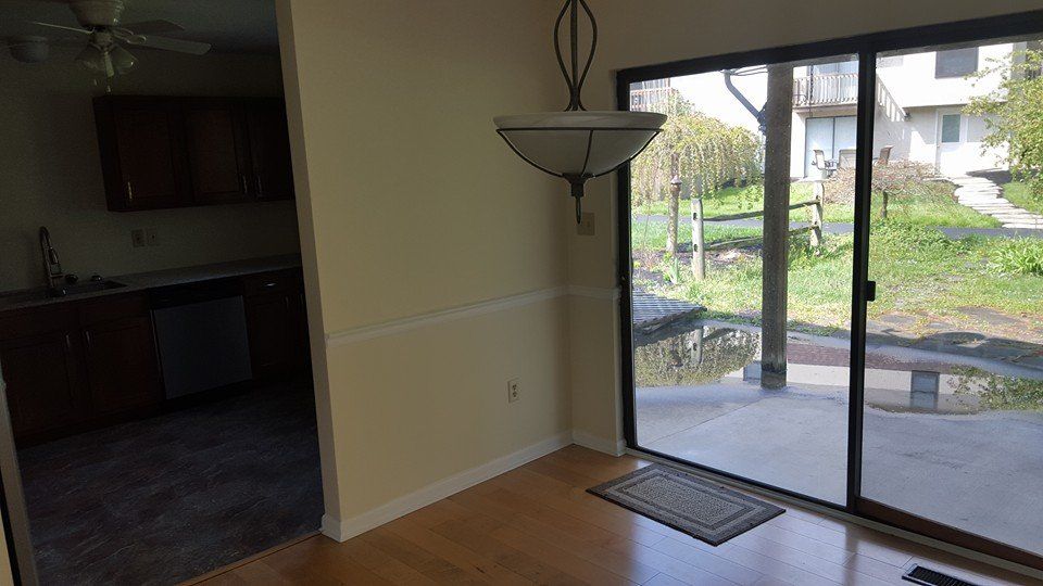 An empty dining room with a sliding glass door and a chandelier hanging from the ceiling.