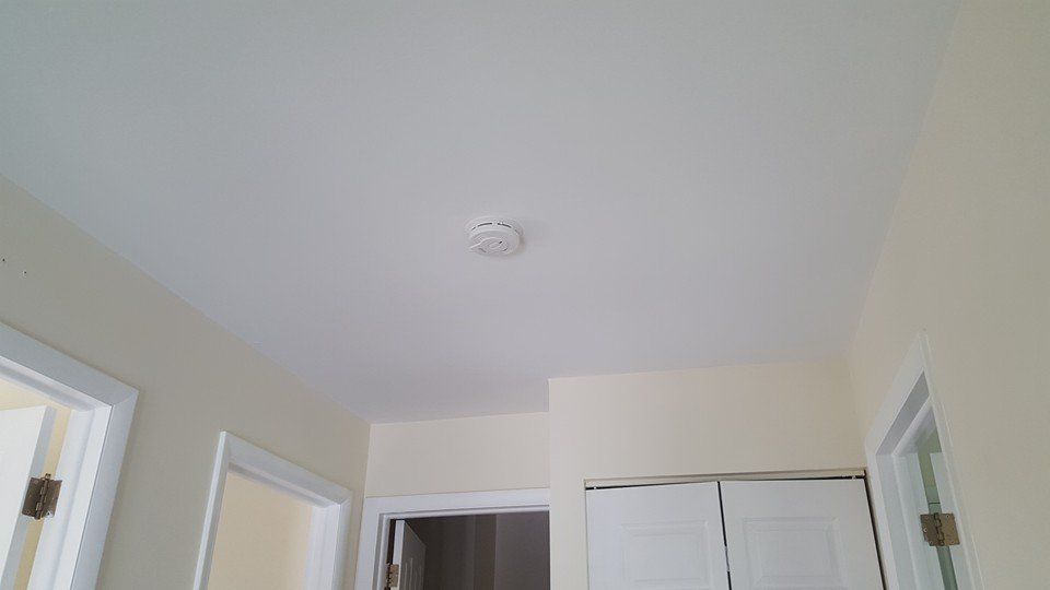 There is a smoke detector on the ceiling of the room.