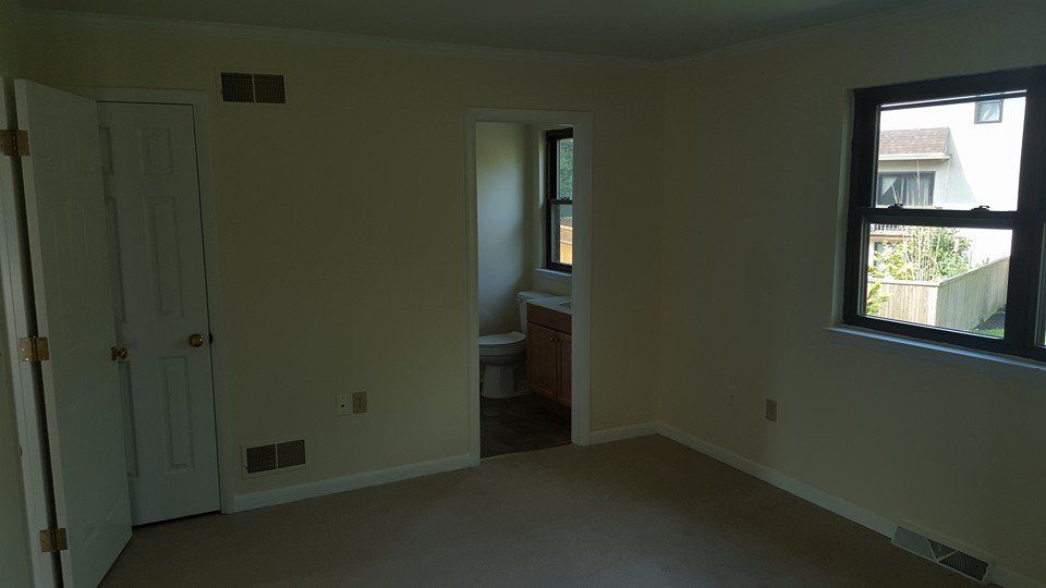 An empty room with a toilet , sink and window.