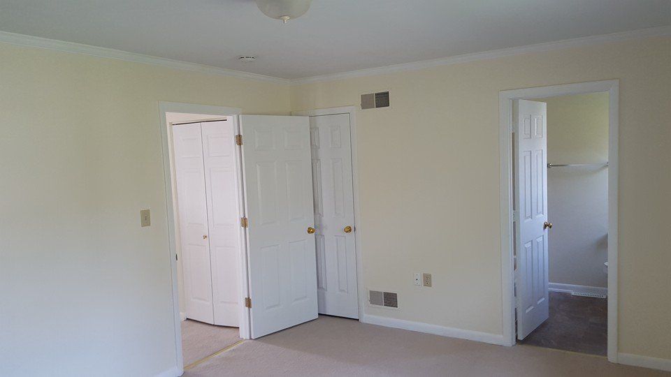 An empty room with white walls and a ceiling fan.