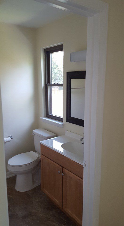 A bathroom with a toilet , sink and mirror.