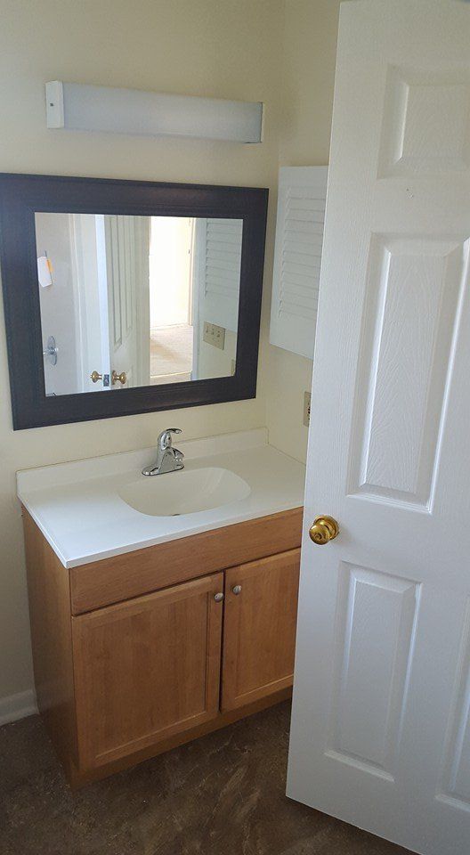 A bathroom with a sink , mirror and cabinets.