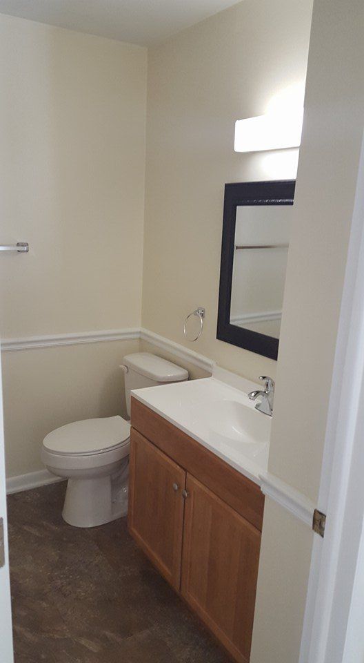 A bathroom with a toilet , sink and mirror.