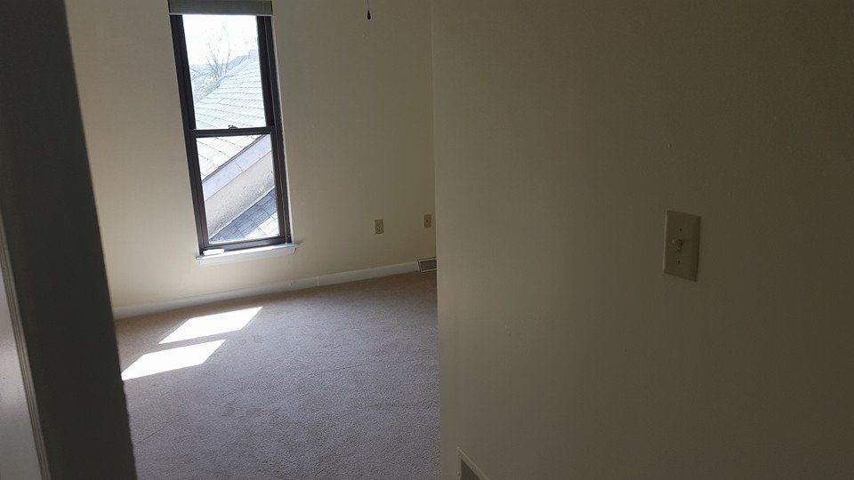 An empty room with a window and a light switch.